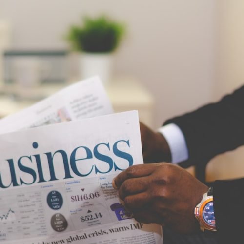 Pessoa lendo um jornal com notícias de negócios