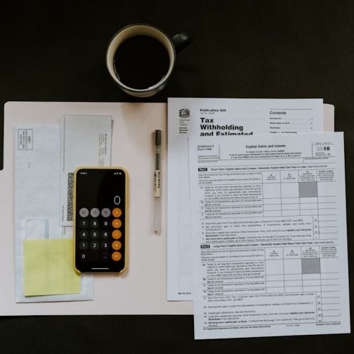 Documentos fiscais, celular e caneta representando a digitalização das obrigações da reforma tributária