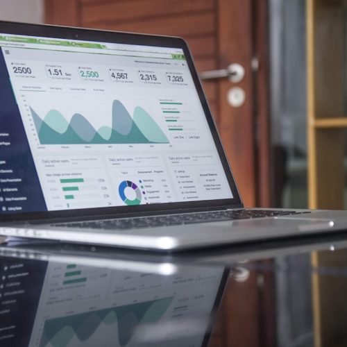 Laptop com gráficos e indicadores de desempenho empresarial representando o Painel Receita